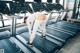 A woman is running on a treadmill in a gym.