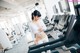 A woman is standing on a treadmill in a gym.