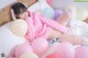 A woman laying on a bed with pink and white balloons.