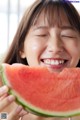 A young girl smiles as she eats a slice of watermelon.