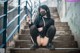 A woman wearing a face mask sitting on the steps of a building.