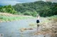 A woman standing in a river with her arms outstretched.