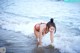A woman in a red bikini standing in the ocean.