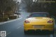 A yellow sports car driving down a street.