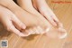 A woman is putting a pair of feet on a wooden floor.