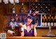 A woman in bunny ears sitting at a bar with a glass of wine.