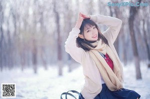 A woman sitting on a bench in the snow.
