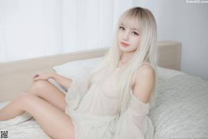 A woman sitting on top of a bed in a white dress.