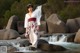 A woman standing on a rock in front of a waterfall.