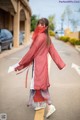 A woman in a red kimono is walking down the street.
